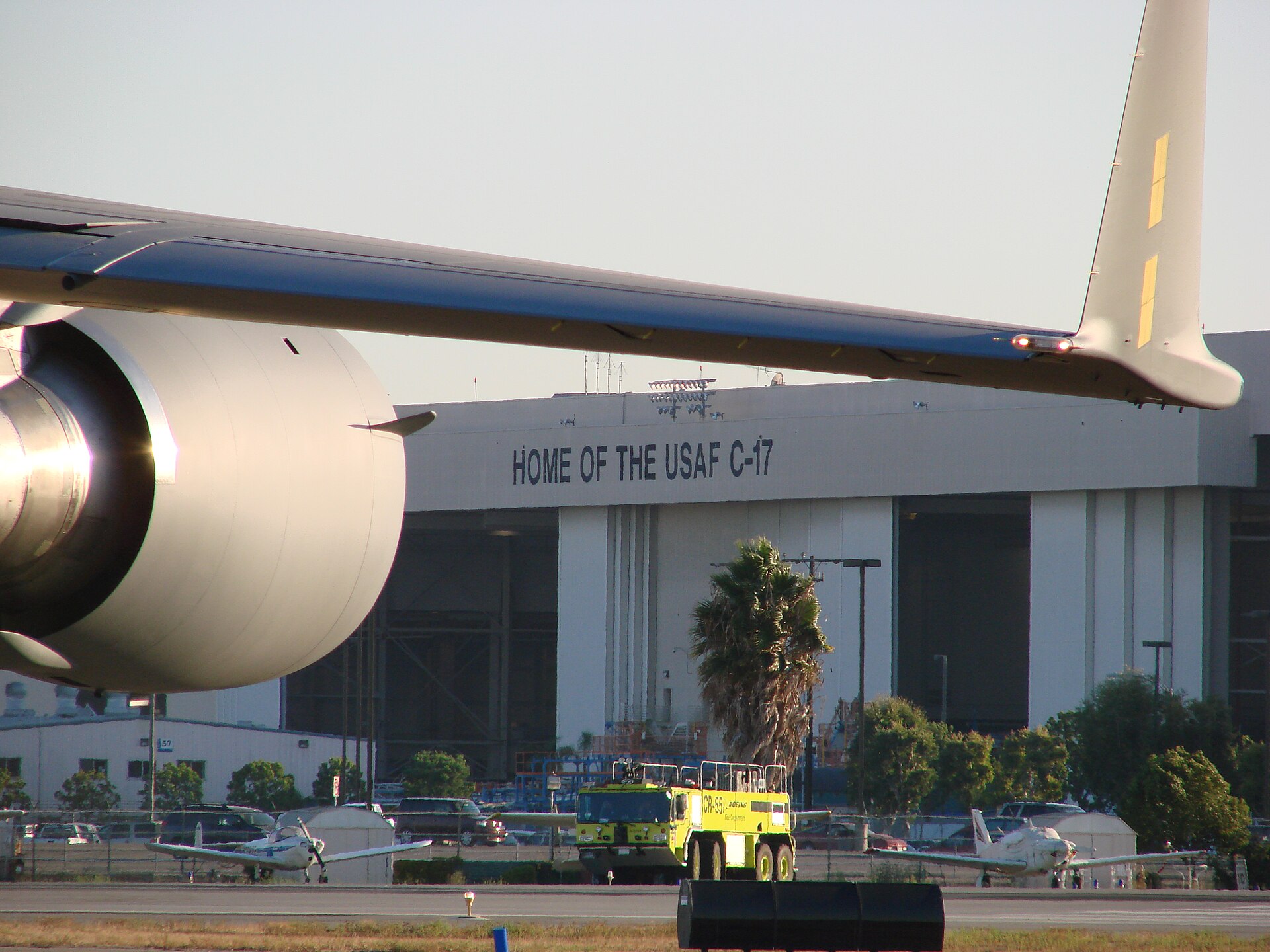 A C-17 wing and engine in front of the Long Beach hangar painted Home of the USAF C-17