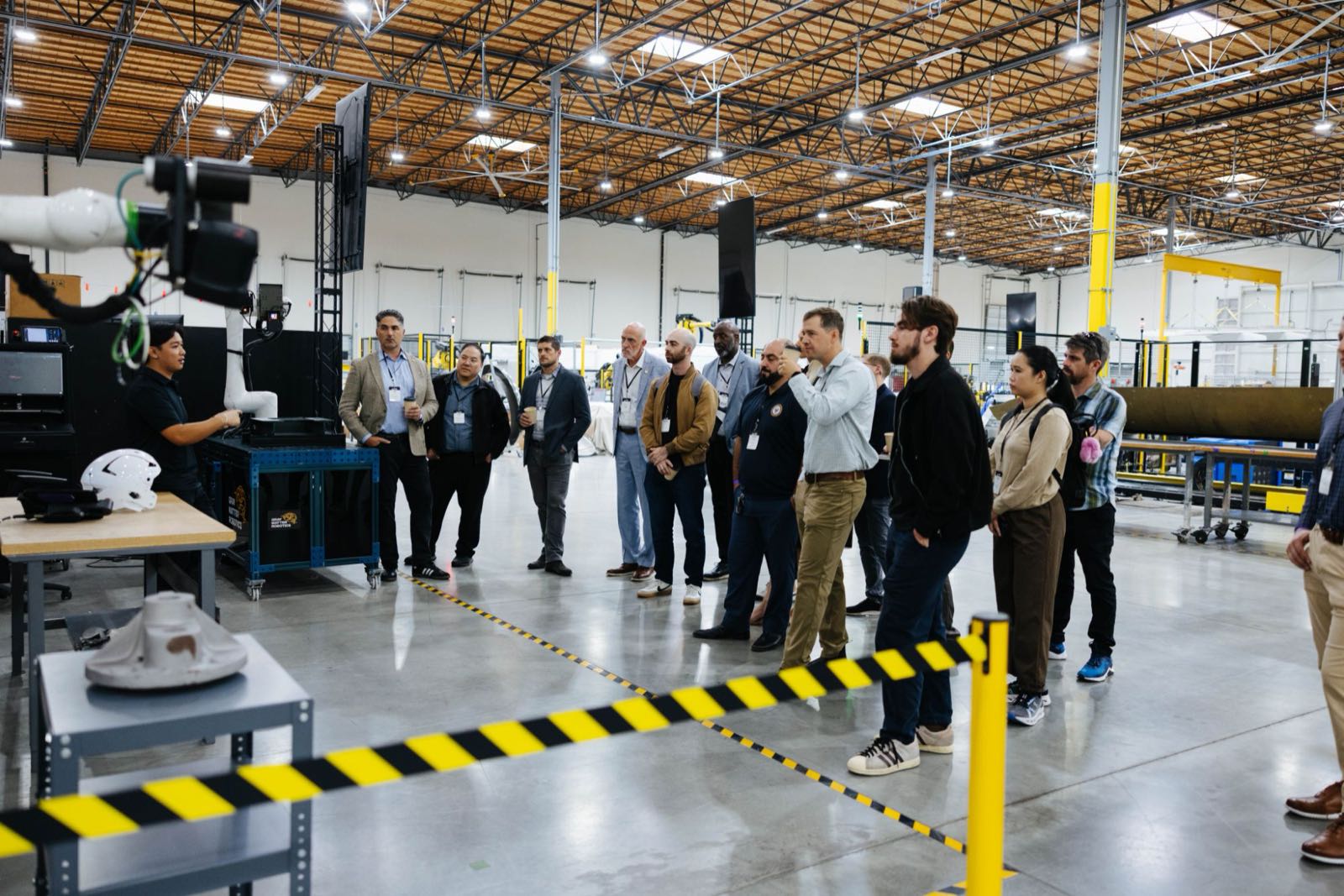 Attendees walking the GrayMatter Robotics factory floor past robotic work cells