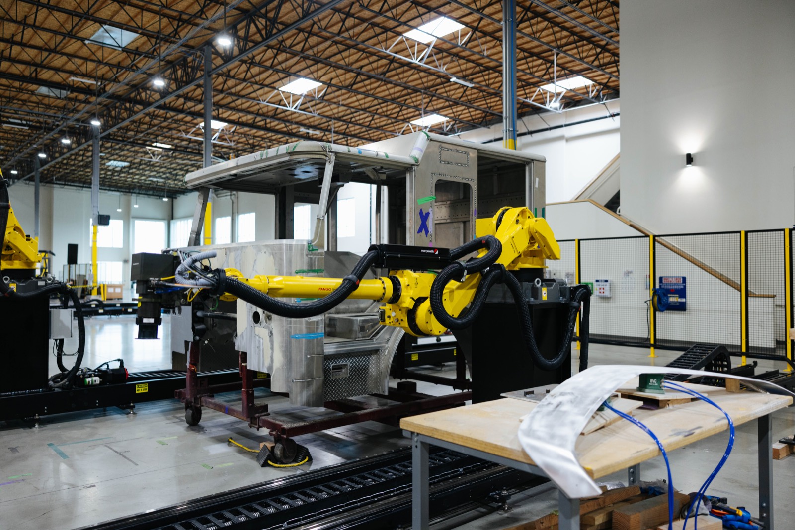 A yellow industrial robot arm in a work cell at GrayMatter Robotics